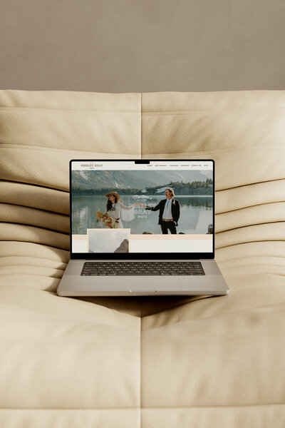 A laptop sits open on a high end leather chair, displaying the homepage banner for Presley Gray Photo who is a luxury Montana and Glacier National Park wedding photographer
