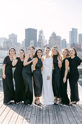 Portrait of the bride and her bridesmaids dressed in black, at Montreal's old port.