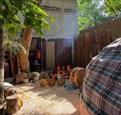 A sacred outdoor space at Ohtly Yancuic in Tulum, featuring a fire pit, ceremonial drums, and a temazcal dome prepared for a traditional Mexican sweat lodge ritual.