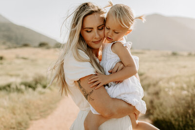 mother and daughter hugging in a field in San Diego, CA