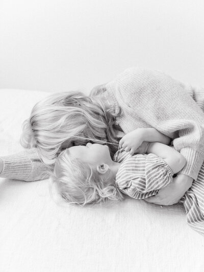 mom and toddler cuddle laying on bed in black and white photo taken by Seattle Newborn and Maternity Photographer Brittany Carvalho
