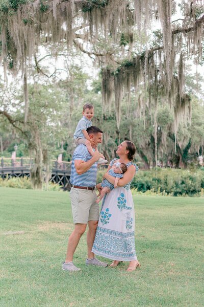 boy on dad’s shoulders, mom holding baby girl under oak trees for Palmetto Bluff photographer Lamp and Light Photography.