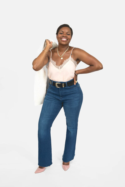 Black career coach for women holding jacket over shoulder in silk top and necklace