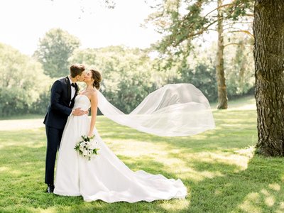 Bride and Groom kissing bride's veil blowing