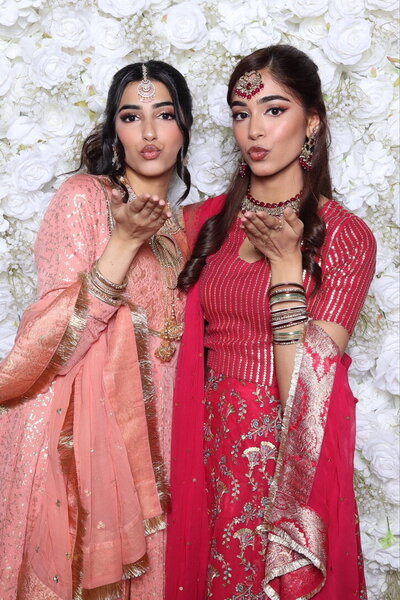 Blowing kisses in front of a white floral backdrop at AR Photobooth.