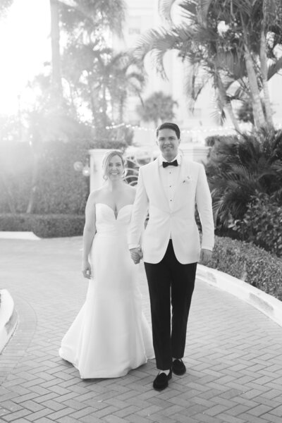 The newlyweds walk together outdoors, glowing in the sun-drenched path of their wedding day.