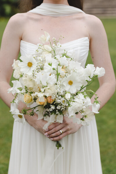 Spring all white wedding bouquet featuring cosmos, garden roses, and sweet peas. 