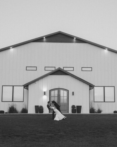 Interior of the August House venue in Dickinson, North Dakota, showing a spacious white-walled wedding reception hall with high ceilings, large windows, minimalist decor, and modern chandelier lighting.