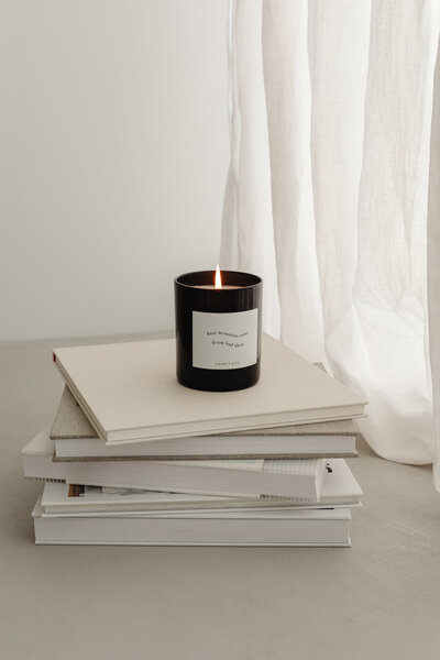 A stack of white books with a black candle on top.