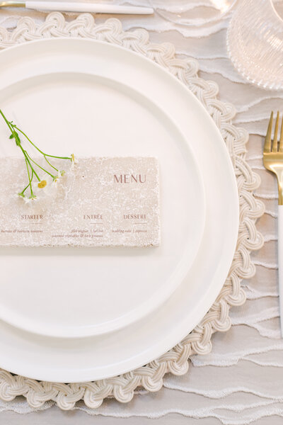 Elegant stone wedding dinner menu with engraved lettering, styled on a neutral table setting and created by Cove Mill Design Co.