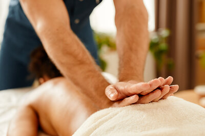Massage therapist performing a firm deep tissue massage on a client’s back.