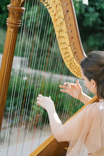 Harpist playing a wedding prelude at an outdoor wedding at DragonRidge Country Club