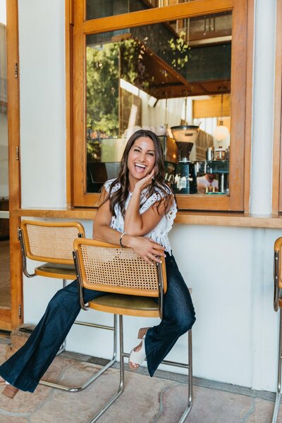 woman sitting backwards in wooden chair laughing