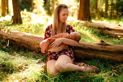 mother seated on grass holding newborn baby