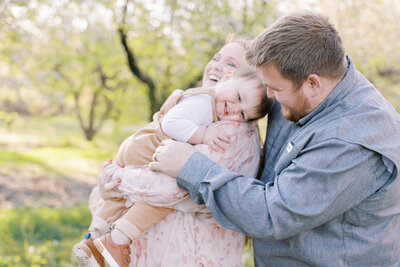 Happy family snuggles together for family maternity session at Cider Hill Family Orchard