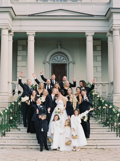 Joyful full wedding party portrait on mansion steps, editorial luxury wedding photography in Washington DC at Great Marsh Estate