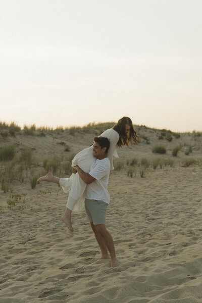 Couple having fun by the beach for their engagement session while man is carrying her girl