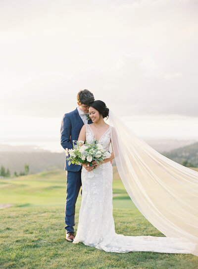 seattle wedding photographers - bride and groom holding each other with veil blowing in the wind at golden hour on a grassy hill