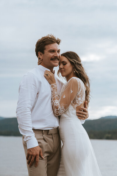 groom laughs with one hand around bride while bride puts her hand on his chest and snuggles up close to him at their elopement in Lake Tahoe by California elopement photographer Kasey Mantiply