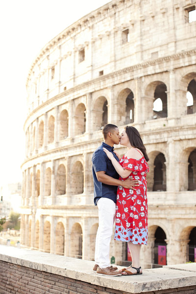 A newly engaged couple kissing in front of the Colosseum. Taken by Rome Engagement Photographer, Tricia Anne Photography