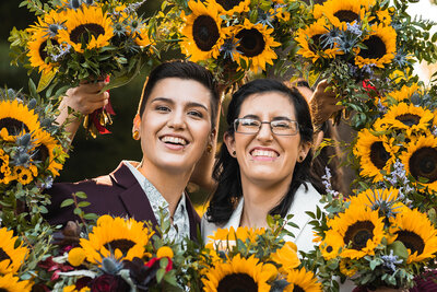 a gay couple smiling for their wedding photos surrounded by florals
