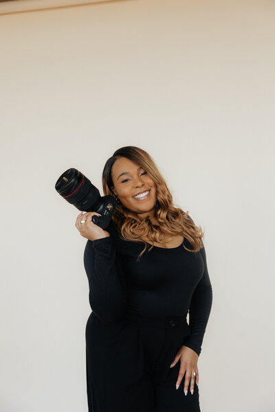 The photographer is posing holding a camera. 