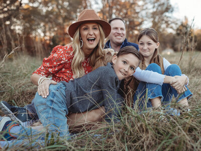 A tween boy acts silly while his family laughs in the background. 