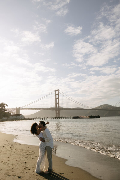 Northern California Wedding Photographer capturing a romantic beach engagement with the Golden Gate Bridge in the background.