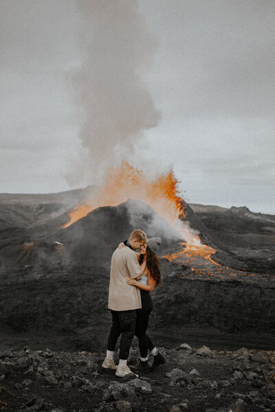 couple holding eachother in front of a volcano
