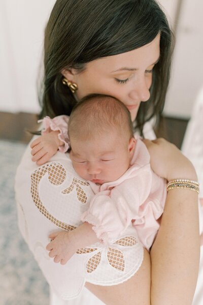 Two brothers peeking on their baby sister through the crib as she sleeps soundly during a lifestyle newborn session in Charlotte, North Carolina.