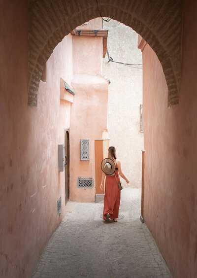 A woman walking down a pink alleyway, symbolizing resilience and transformation in her coaching journey.