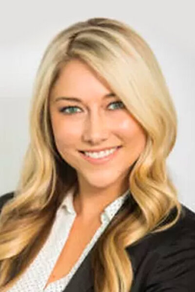 Headshot of a young blonde woman wearing a black blazer over a white blouse.