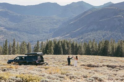 A bride and groom clink beer cans while taking in an epic mountain view from a forest service road in Mammoth Lakes. 