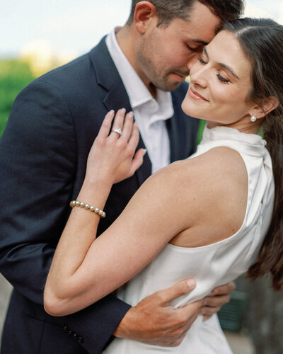 Engaged couple sitting close on city steps during golden hour in Pittsburgh, sharing a sweet moment together