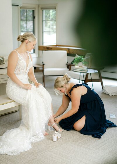 Bride getting ready for her wedding day in Columbus, OH, with her mother assisting her with putting on her shoes. A heartfelt and intimate moment of preparation.