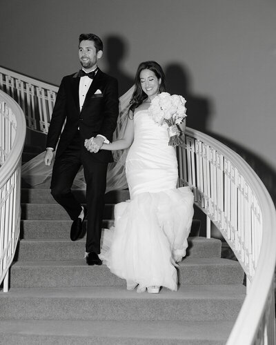 black and white photo of bride and groom descending spiral staircase holding hands image by tom thornton minnesota photographer