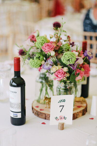 Wine bottle with jar of flowers with table number 7