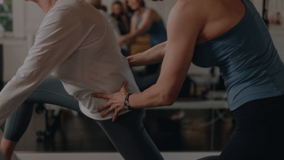 woman assisting a client on a pilates reformer 