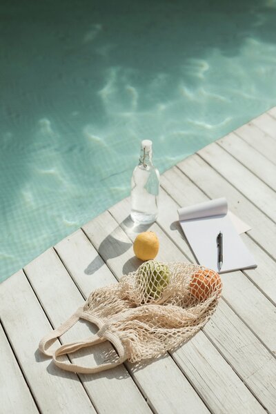 Newsletter What's Included  Notebook Bottle Orange on Wood next to water sunny vibes