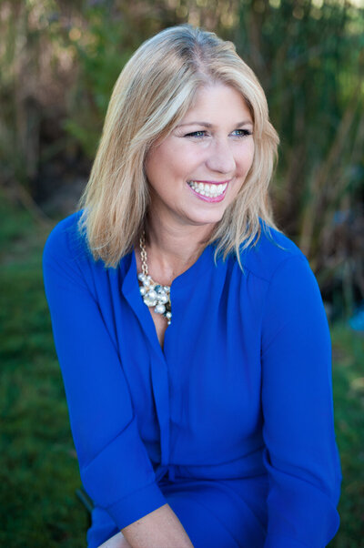 Creative Headshot of a caucasian woman with blonde hair and royal blue dress laughing and looking off camera.