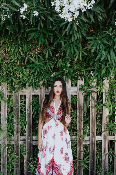 teen girl with bold red lips and floral dress posing for her senior portraits in Southern California