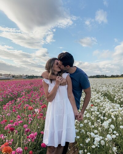 man and woman kissing in field with flowers