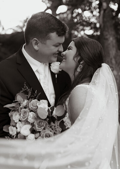 bride and groom almost kissing and holding floral bouquet