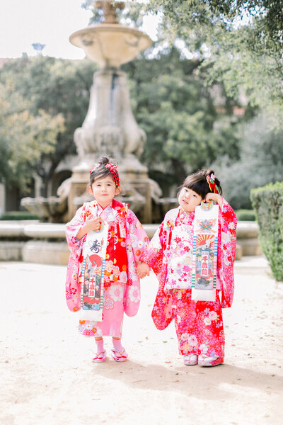 Two young girls in pink kimono celebrating Shichi-Go-San (七五三) children’s ceremony with traditional Japanese style.