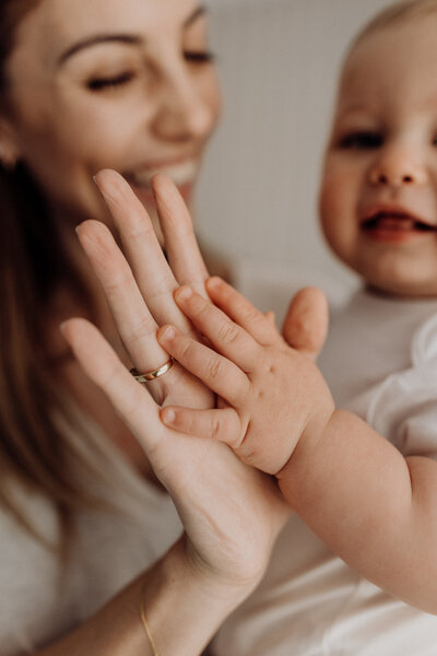 a mother and childs hands held up to one another while their faces are blurred out in the background