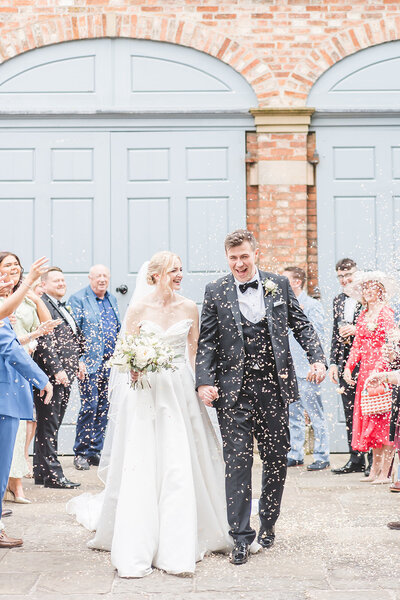 Bride and groom walk through confetti at dorfold hall cheshire