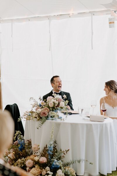 groom laughing during wedding reception toasts