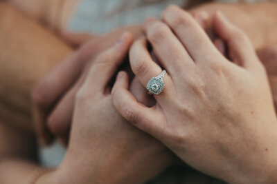 Close-up of newly engaged couple during their Albury engagement and elopement shoot, hands wrapped around her chest highlighting the engagement rings.