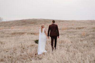 Married Couple walking hand in hand in the dried grass