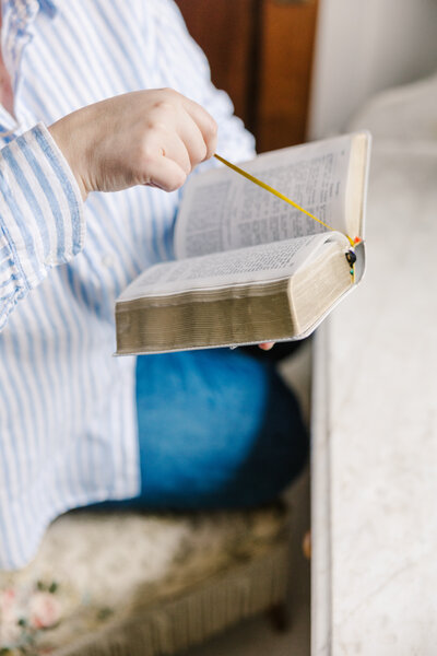 Hands placing a bookmark inside the pages of a Bible